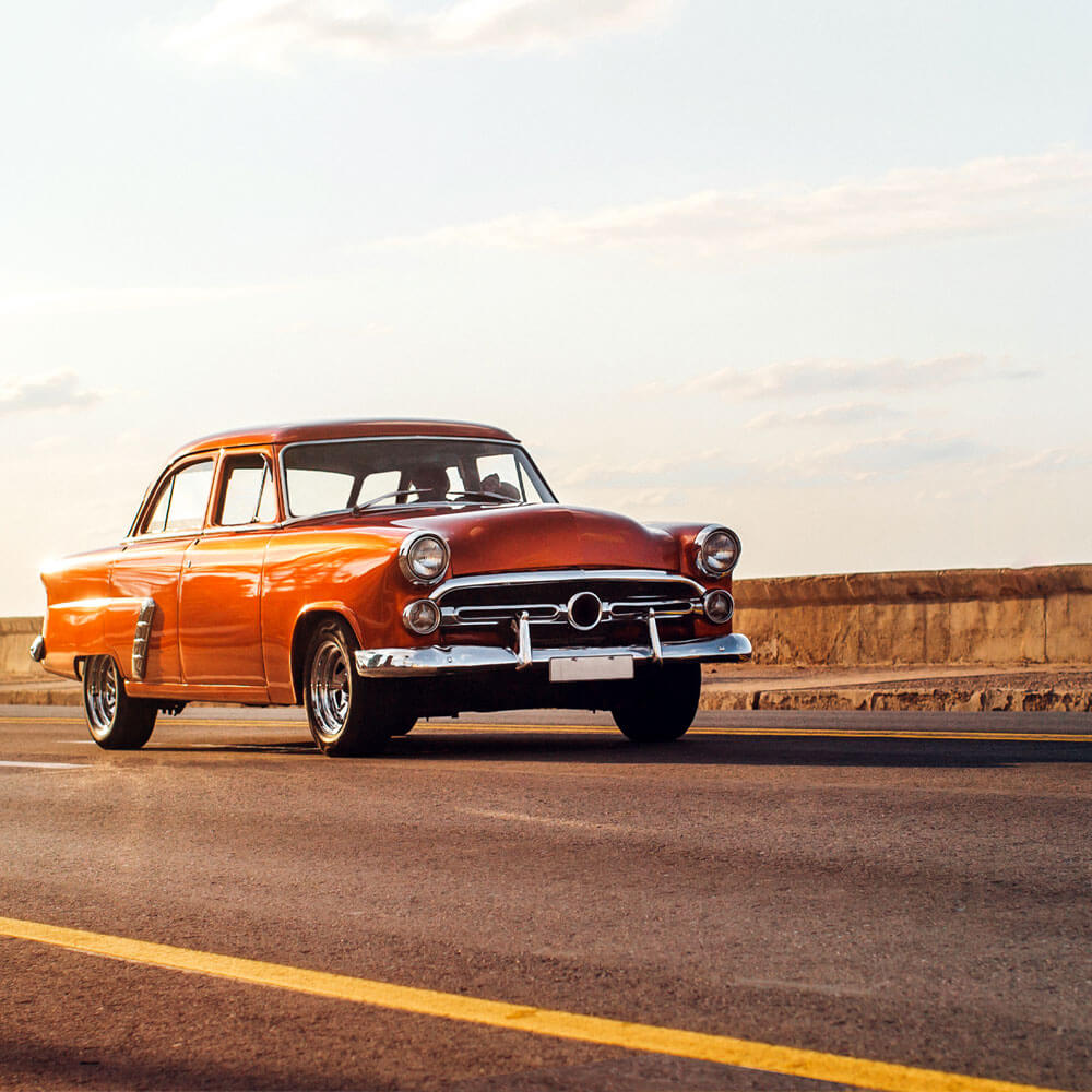 classic car driving during sunset on a summer day