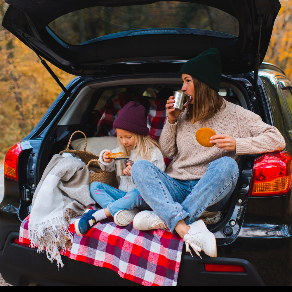 Mother and Daughter enjoying Fall snacks sitting in the trunck of a new car