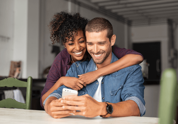 happy diverse couple smiling and looking at certificate growth on phone