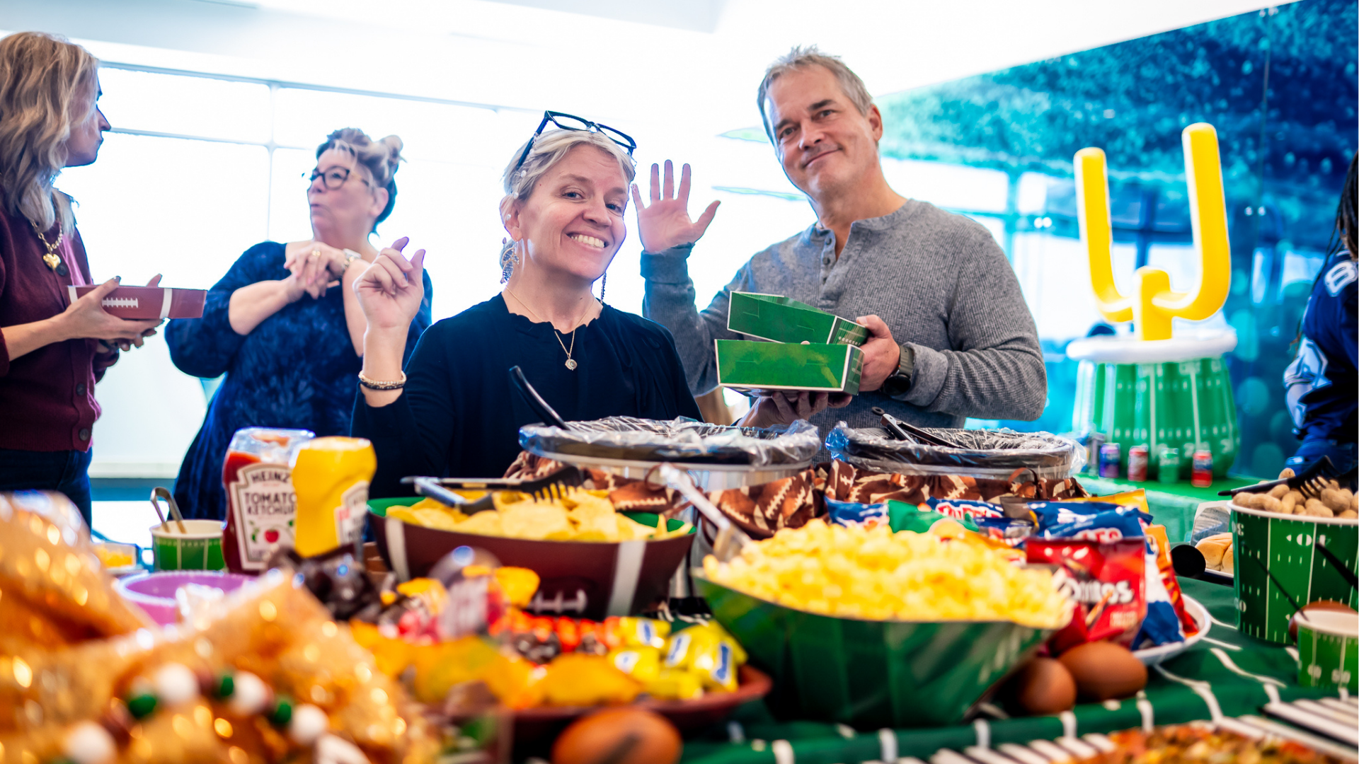 smiling advancial employees waving at advancials super bowl social
