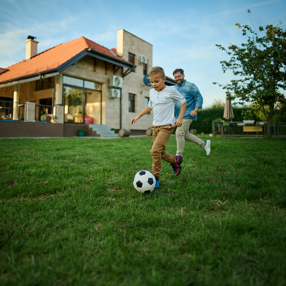 father and son playing soccer in their newly redone home backyard