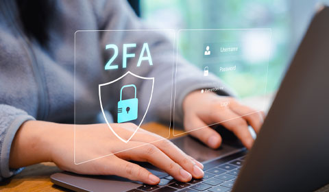 person typing on laptop with a graphic representing two-factor authentication