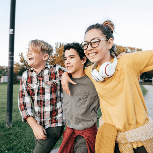 three teens laughing and walking outisde on a bright day