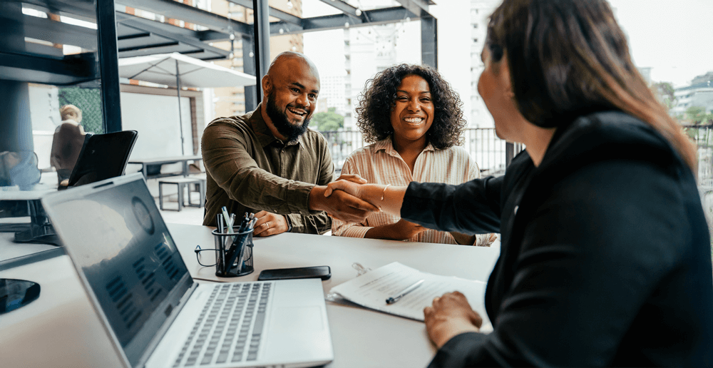 happy couple shaking hands with a financial advisor