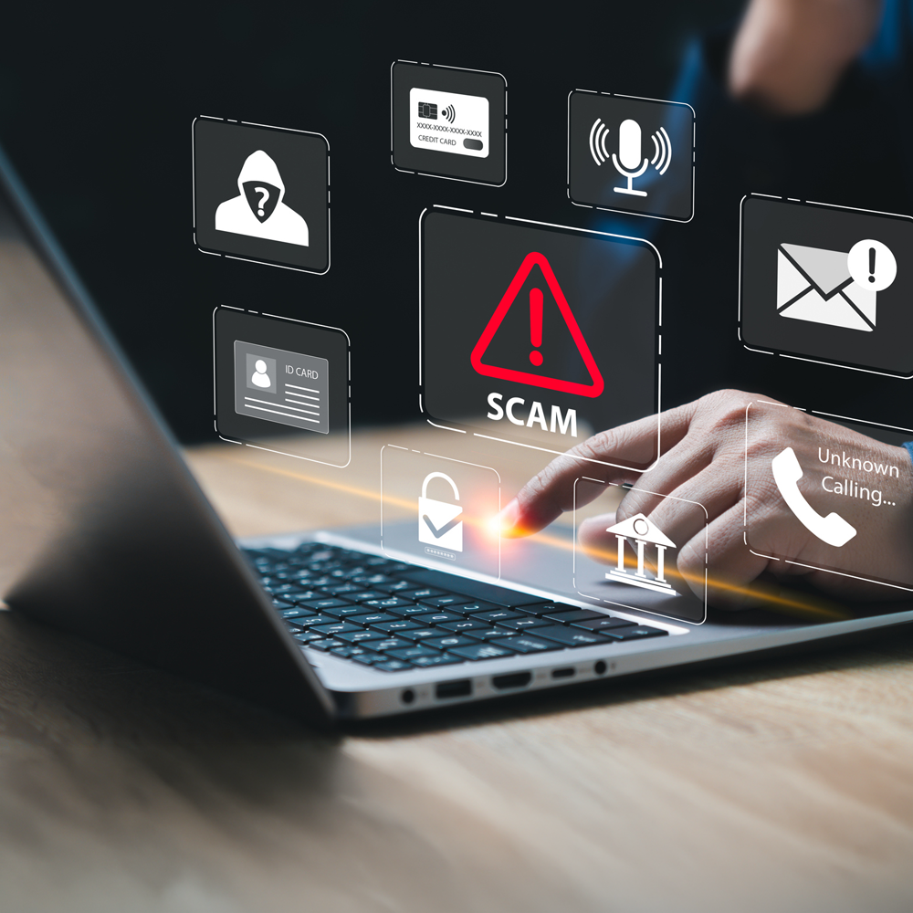 fraudster on laptop with floating "scam" graphics 