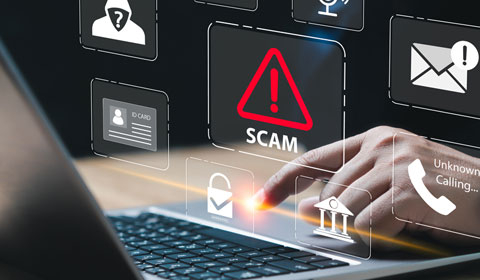 fraudster on laptop with floating "scam" graphics 
