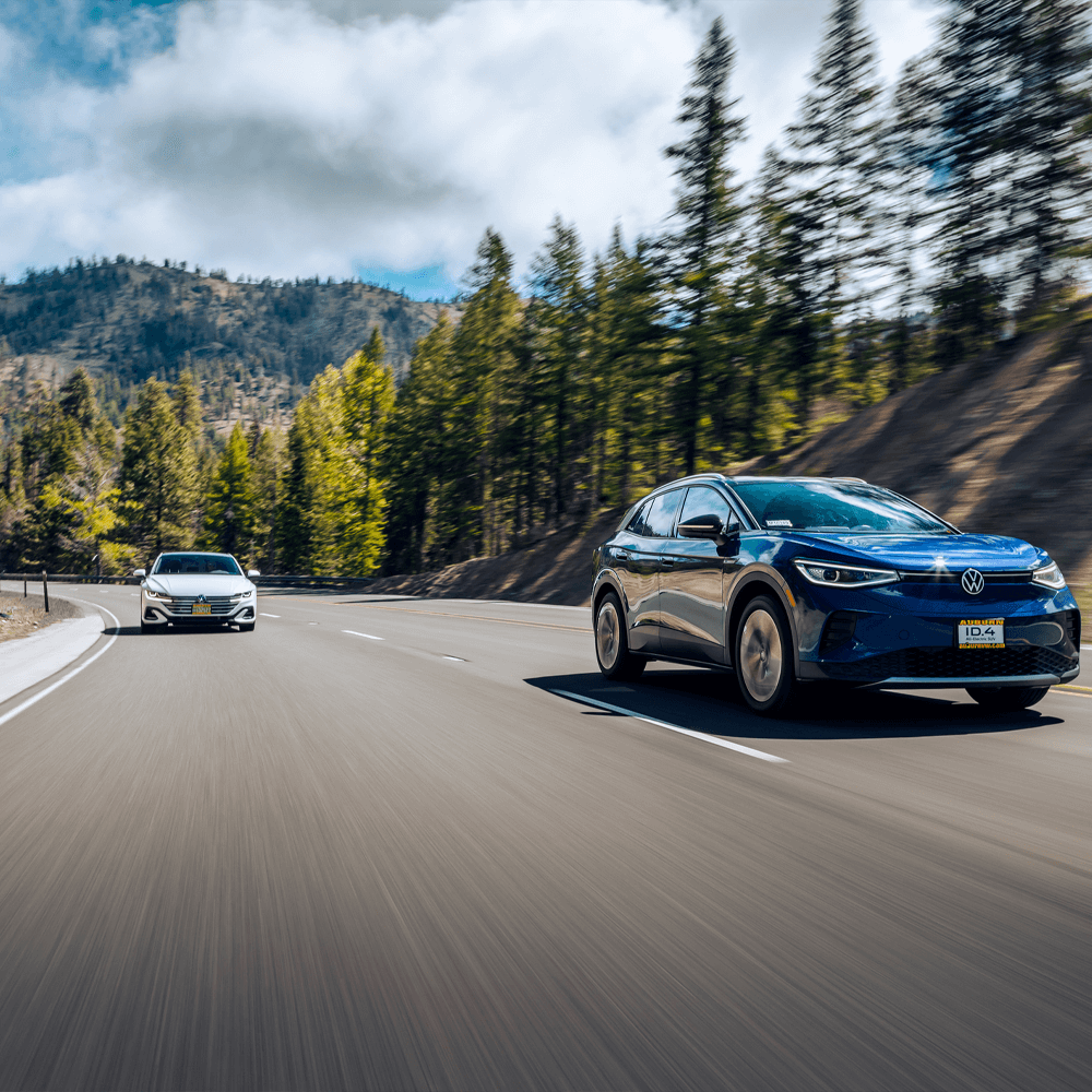 two new cars driving on a road between mountains