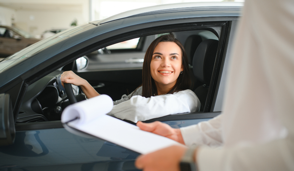 young woman in a new car speaking to car salesman