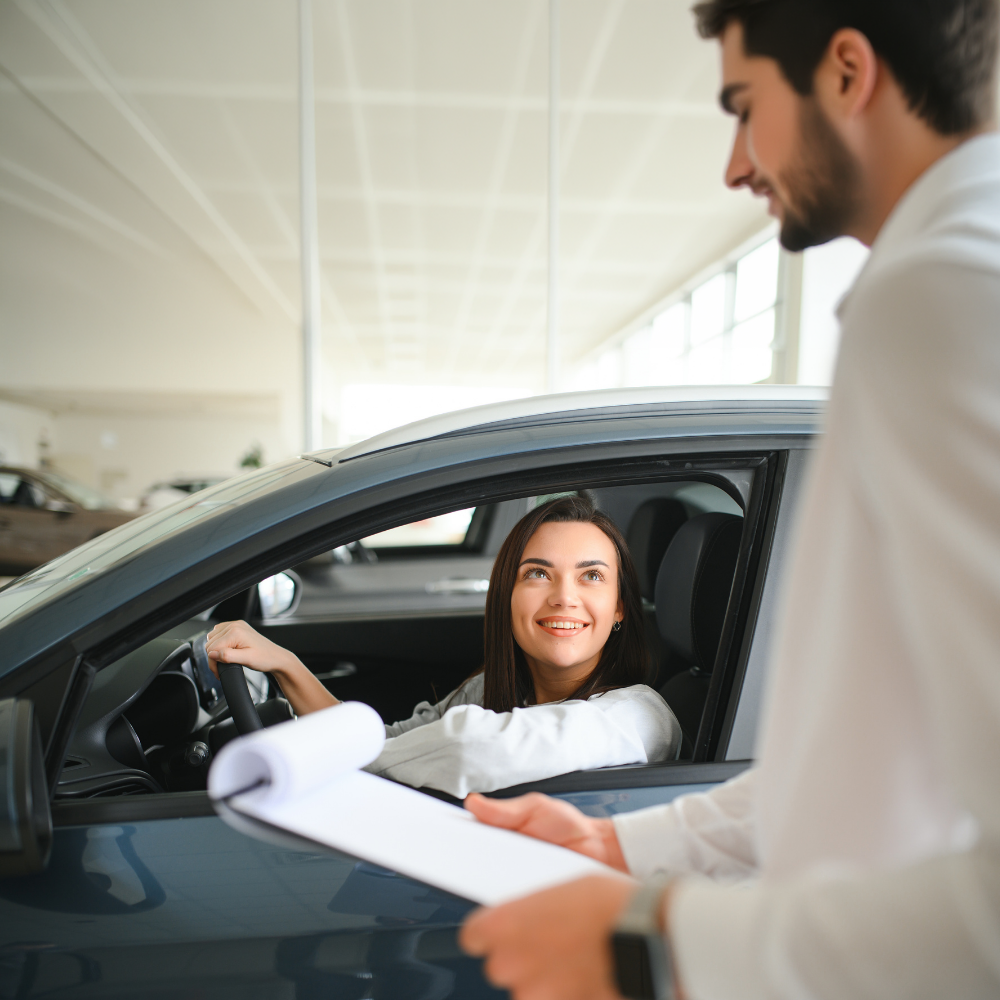 young woman in a new car speaking to car salesman