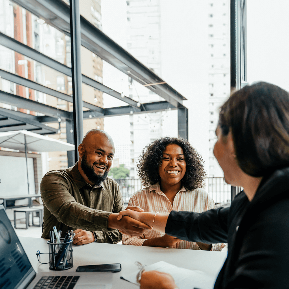 happy couple shaking hands with a financial advisor