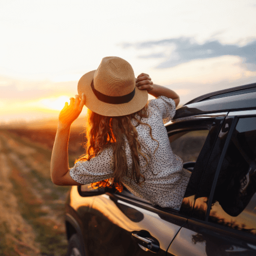 woman wearing a hat poking out of her car window